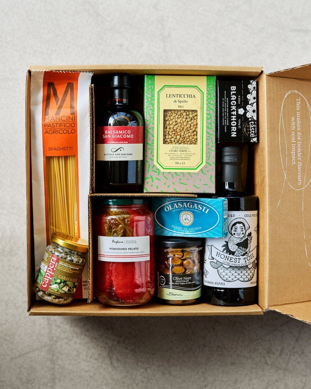 Gourmet Italian food gift box with pasta, vinegar, and various preserved condiments.