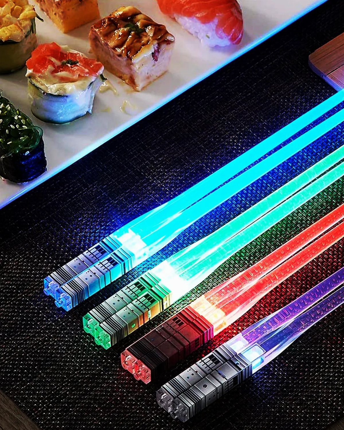 Glowing lightsaber chopsticks in various colors resting beside a plate of sushi rolls.