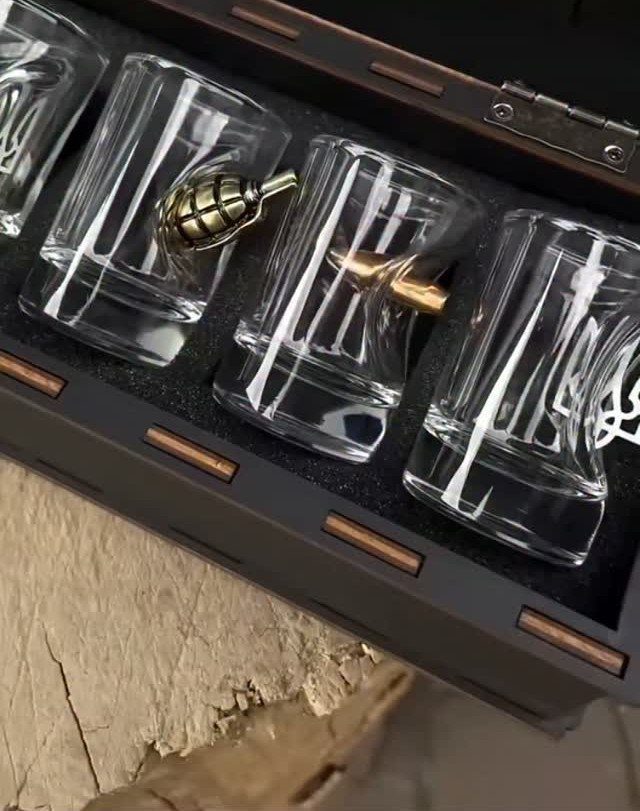 Whiskey glasses with molded grenade and bullet designs in a wooden gift box