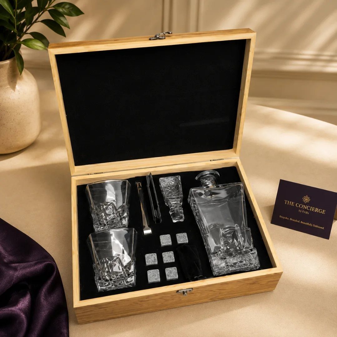 Crystal whiskey decanter and glasses set inside a wooden gift box with accessories.