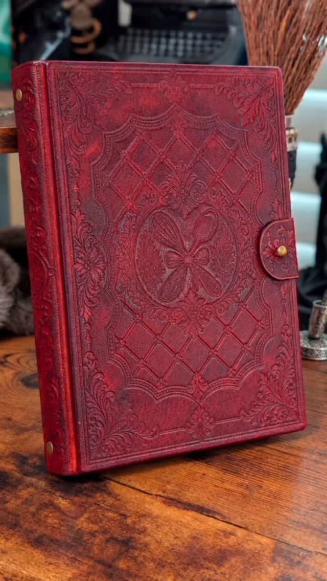 Red embossed leather journal with intricate patterns on a rustic wooden table