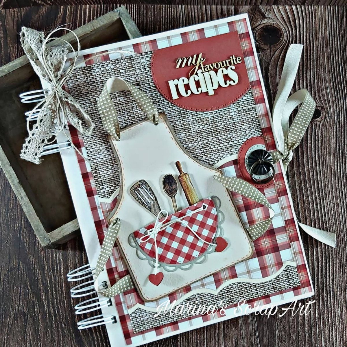 Handmade recipe binder with a red checkered cover and apron decoration on wood.