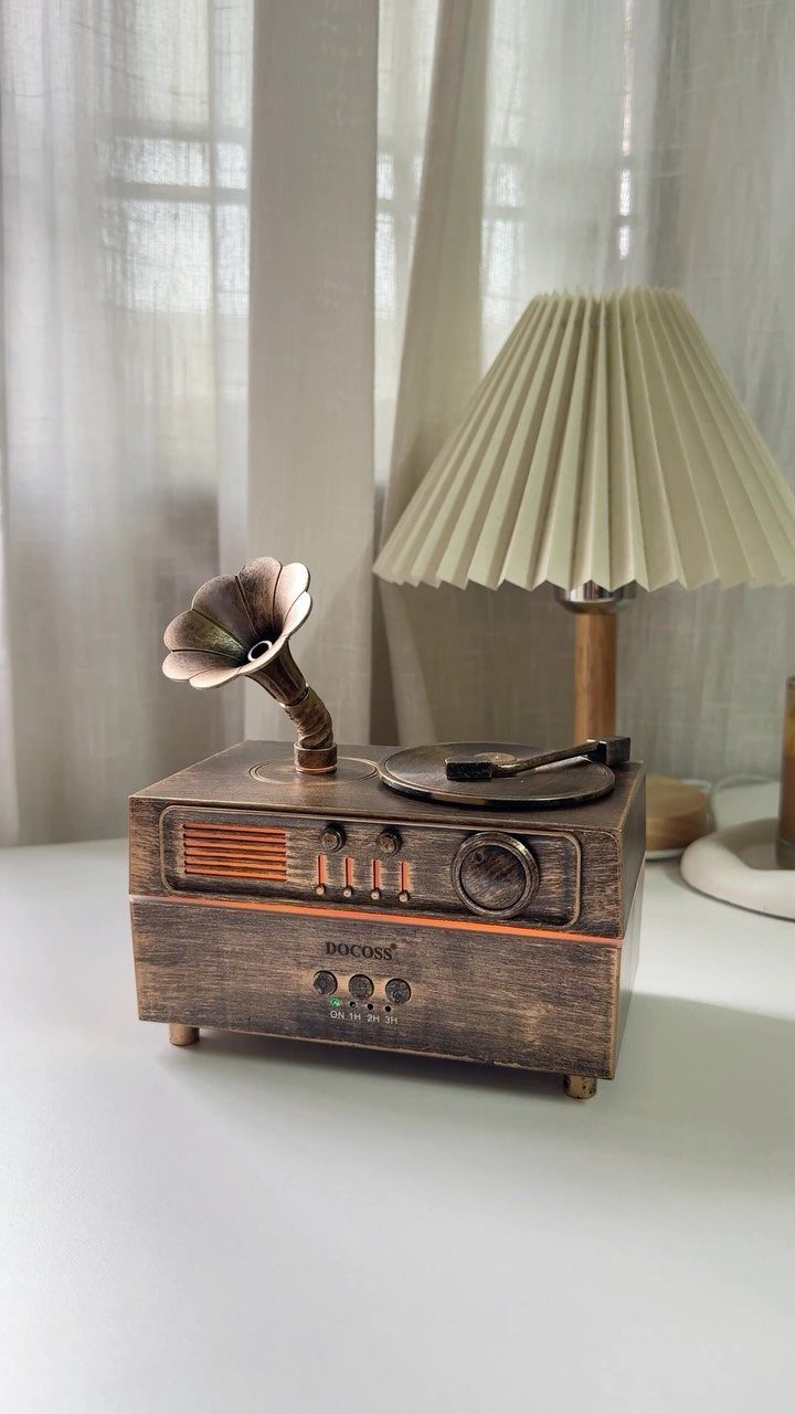 Vintage wooden record player with horn speaker next to a pleated cream lamp