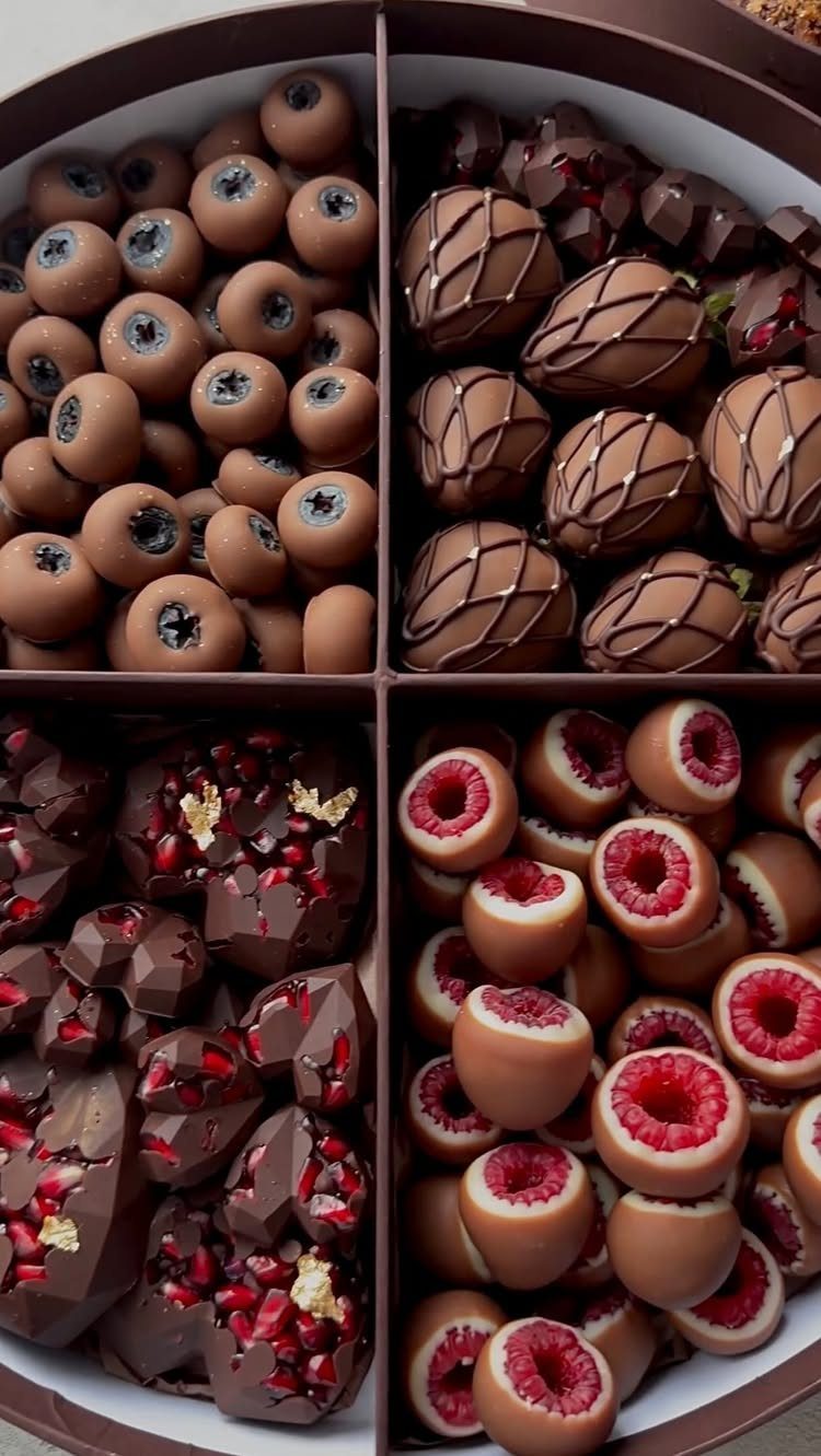 Assorted gourmet chocolates including berry-filled pieces in a divided round gift box.