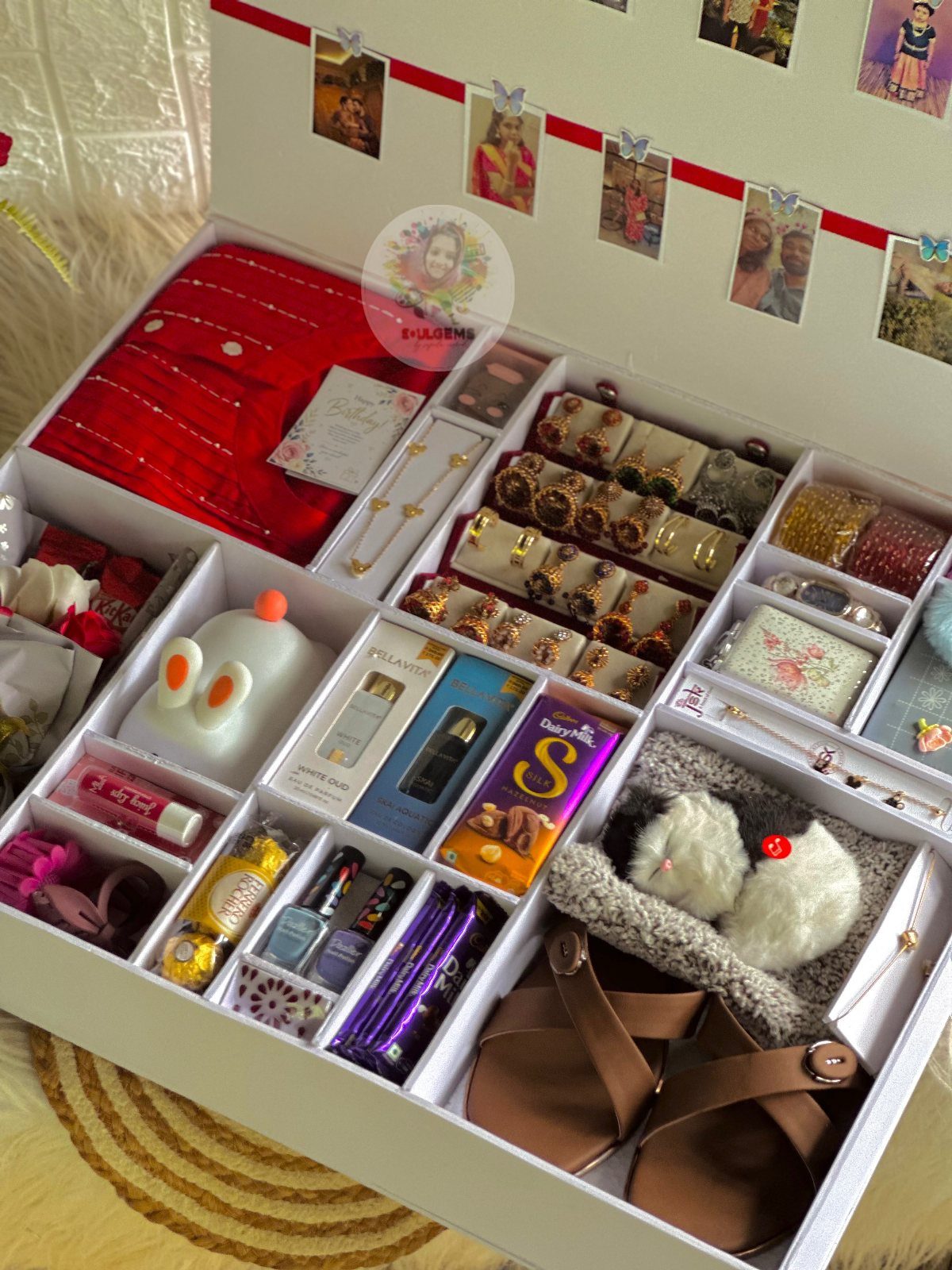 White gift box filled with jewelry, skincare, sandals, and personalized photos on lid.
