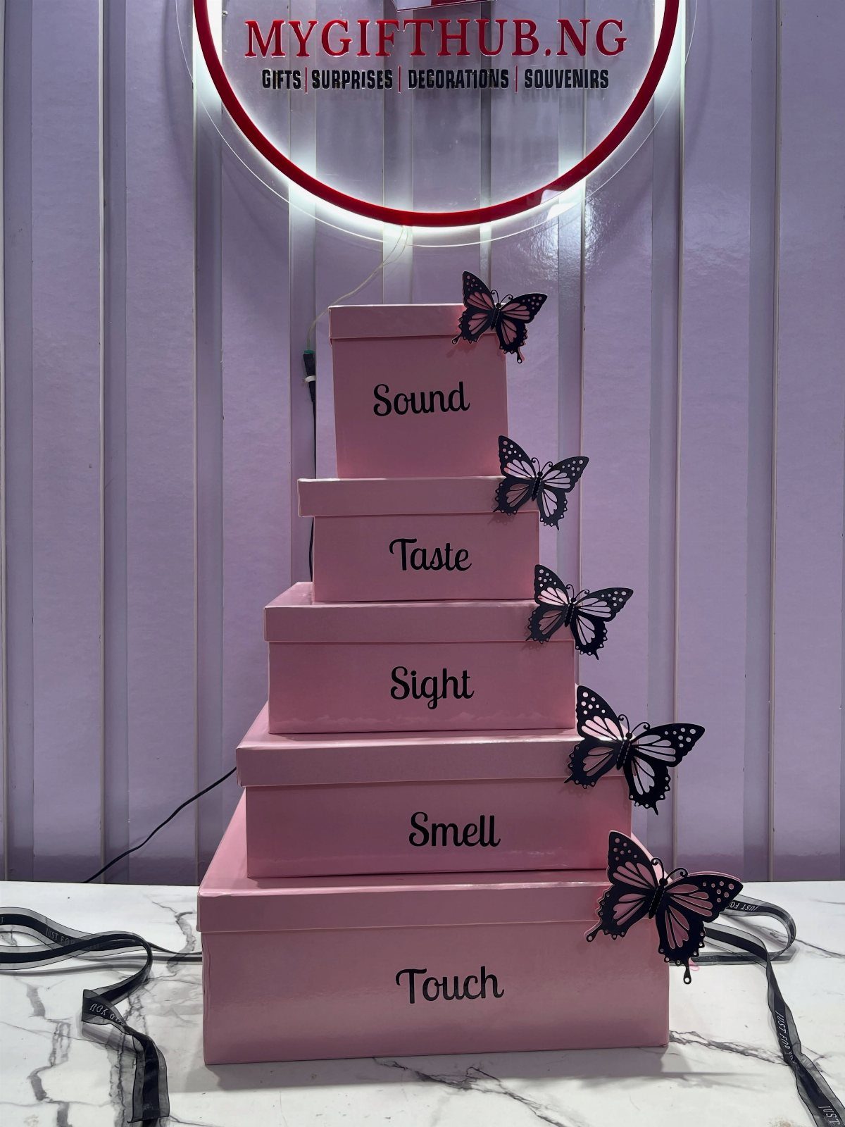 Stacked pink gift boxes labeled with the five senses and decorated with butterflies.