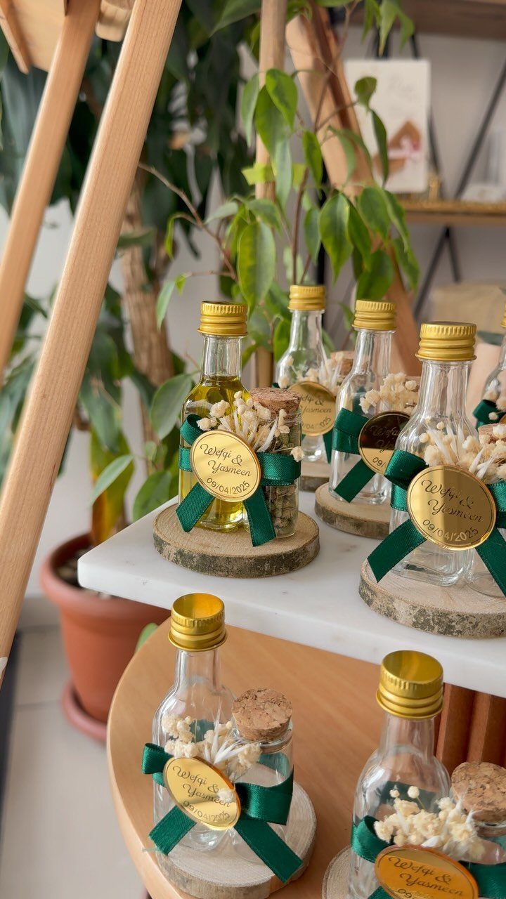 Small glass bottles of olive oil with gold labels and green ribbons on coasters.