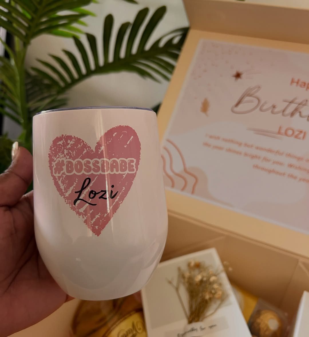 White stemless wine tumbler with pink heart and personalized text held by hand.