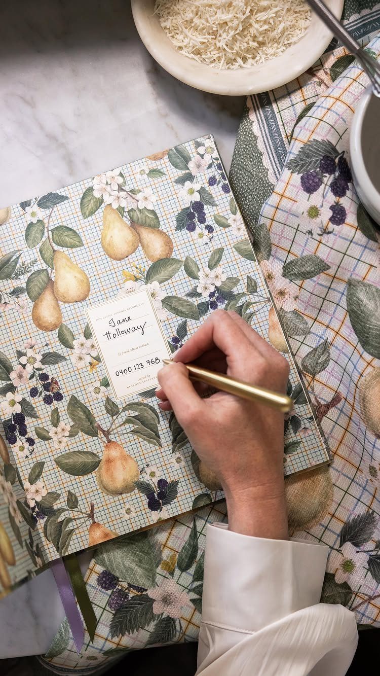 Hand writing on a label of a floral recipe book on a marble counter