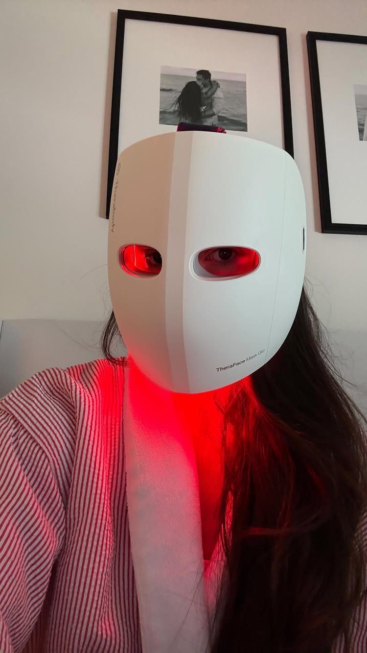 Person wearing a white TheraFace Mask Glo device emitting red light over their face.