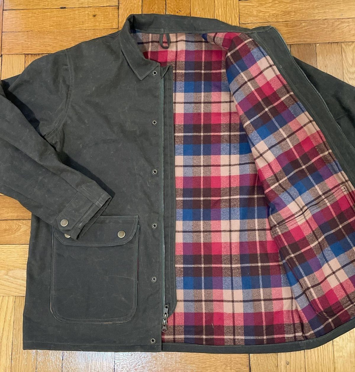 Dark grey canvas jacket with a red and blue plaid flannel lining.
