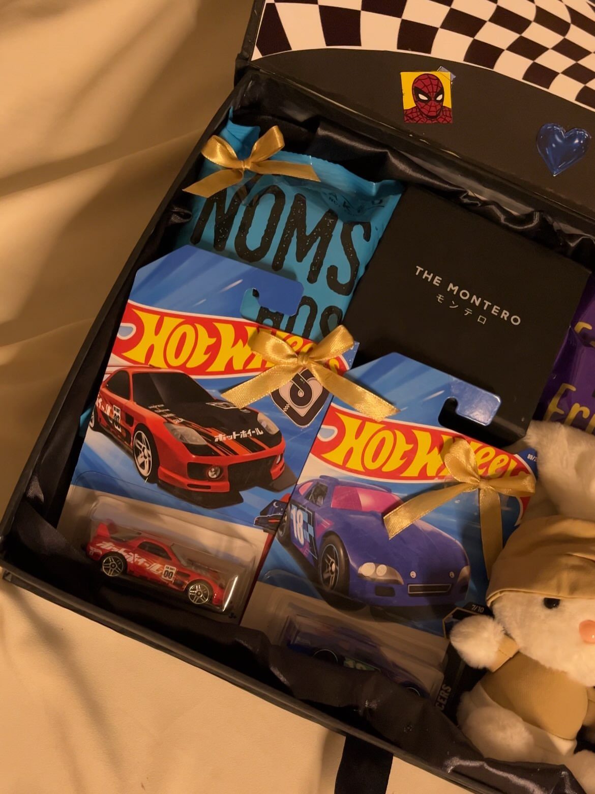 Gift box filled with Hot Wheels cars, a book, snacks, and a plush toy.