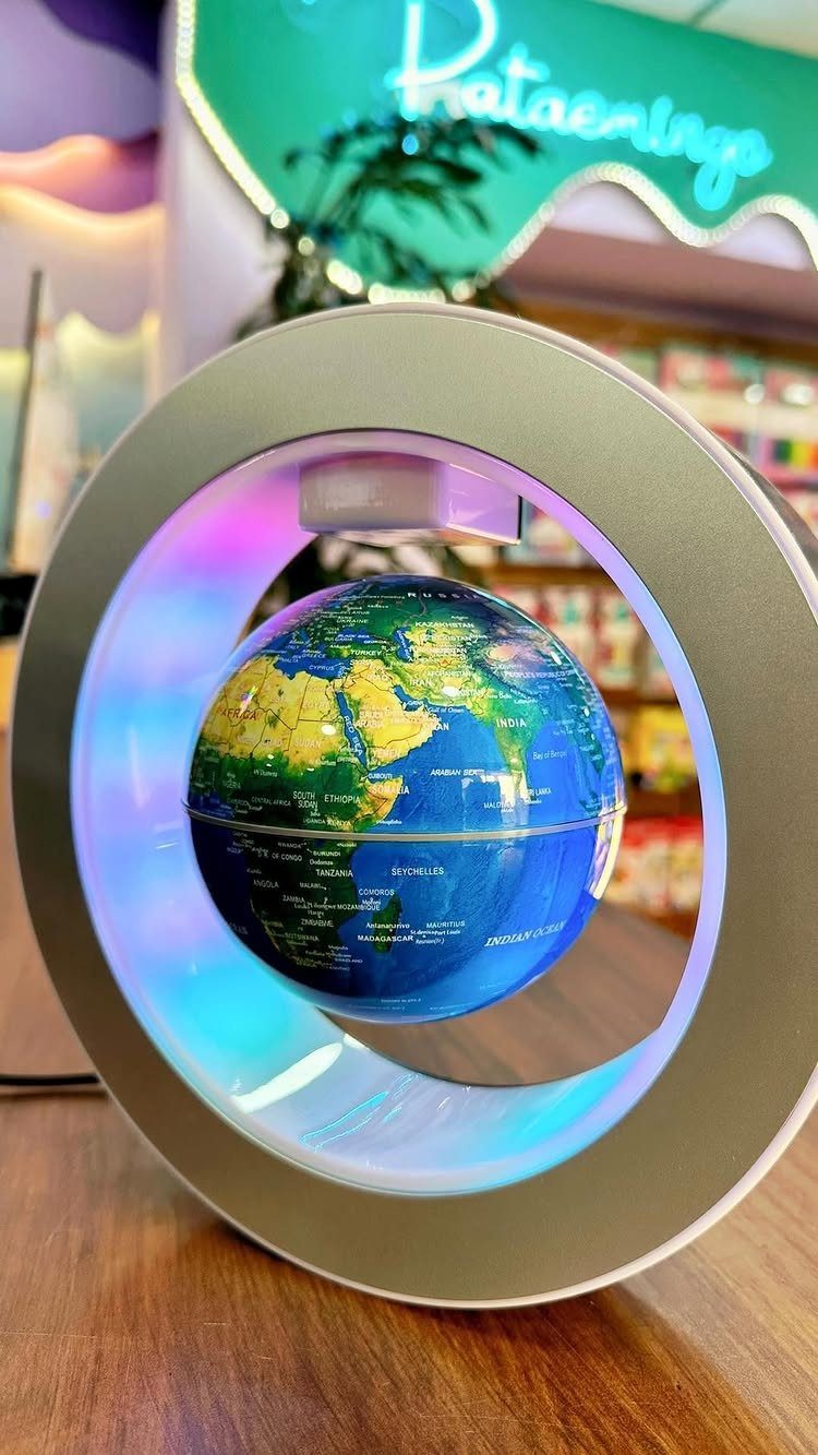 Magnetic levitating globe floating inside a circular silver frame with colorful LED lighting.