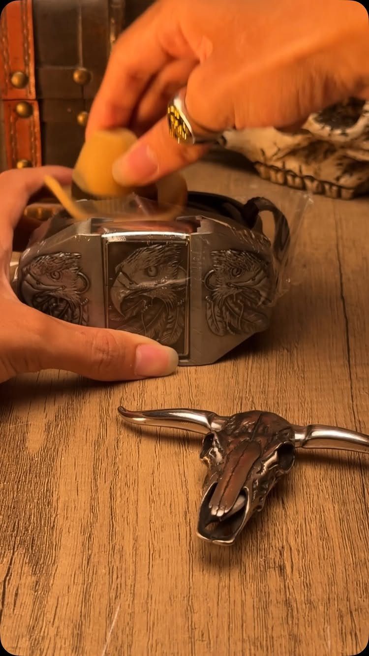 Ornate silver eagle belt buckle being unwrapped on a rustic wooden table