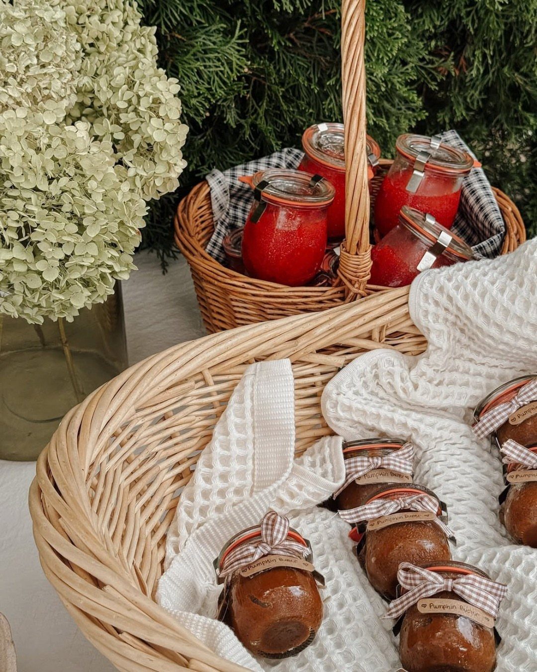 Small jars of brown pumpkin butter with ribbons in a wicker basket