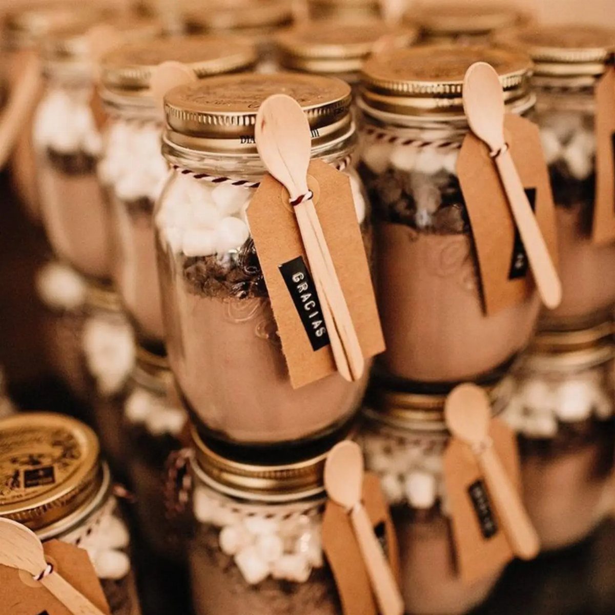Mason jars filled with hot chocolate mix and marshmallows with wooden spoons.