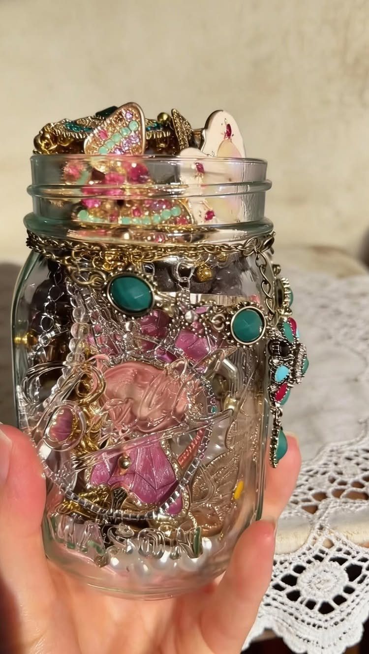 Mason jar filled with gold jewelry and turquoise accessories held in a hand.