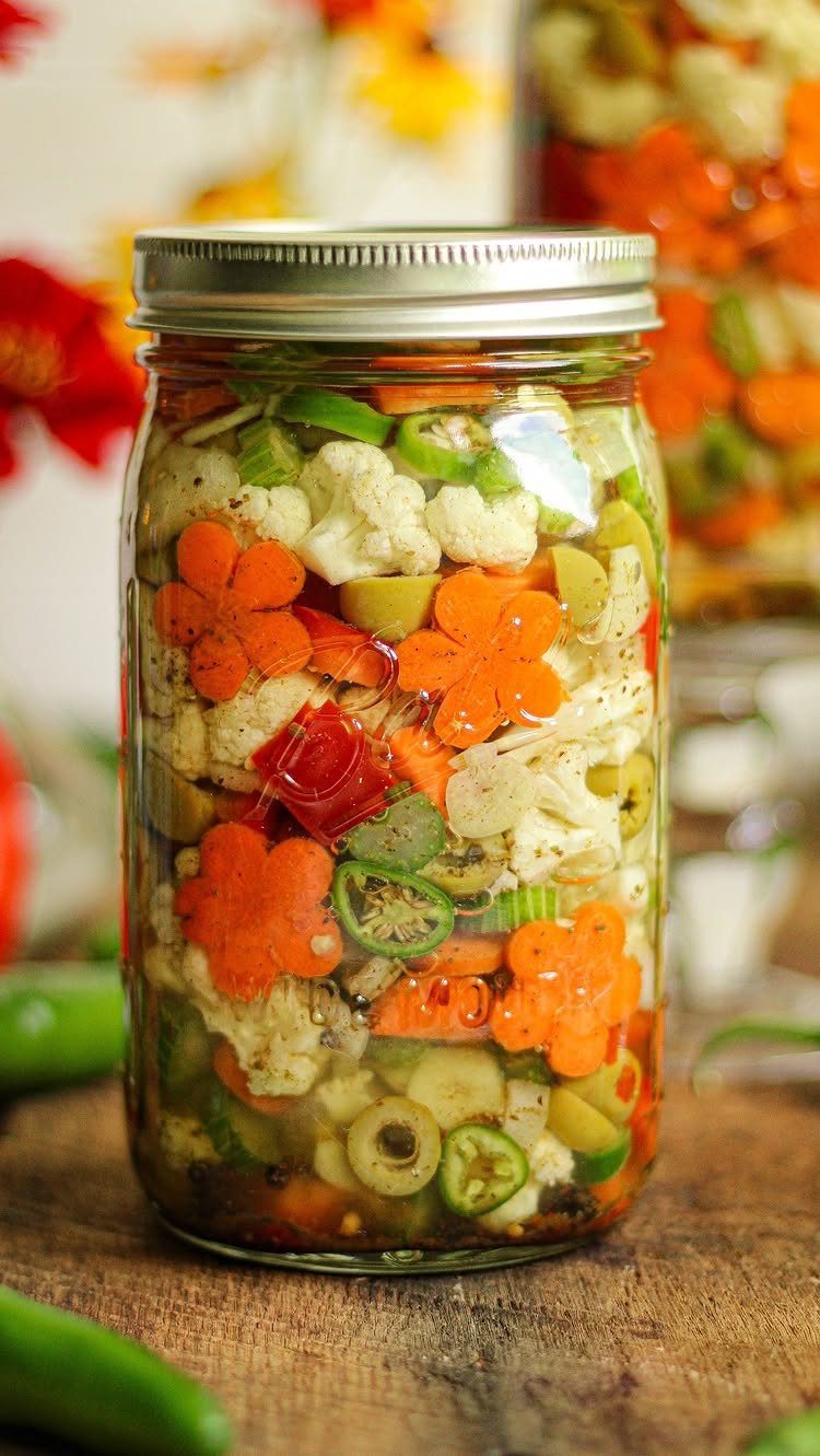 Mason jar filled with colorful pickled cauliflower, carrots, olives, and green peppers.