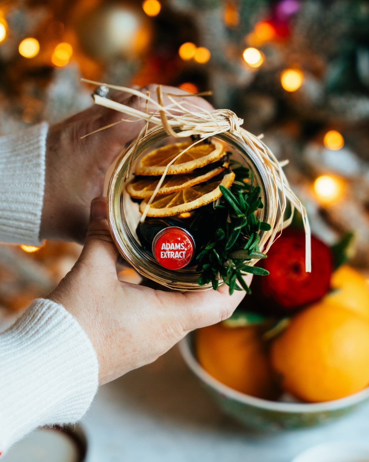 Mason jar filled with dried orange slices and rosemary tied with raffia bow.