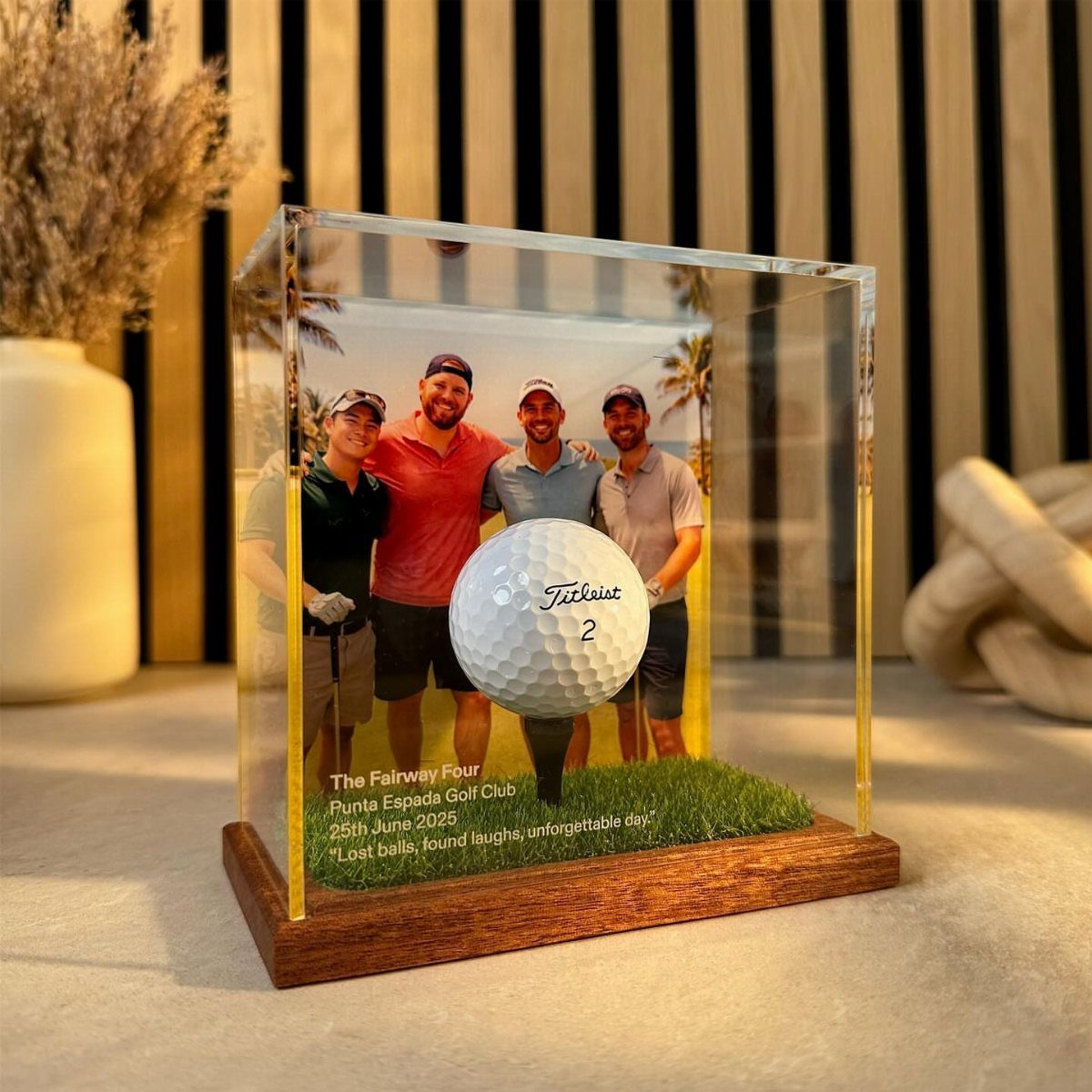 Acrylic display case with a golf ball, artificial grass, and photo of golfers.