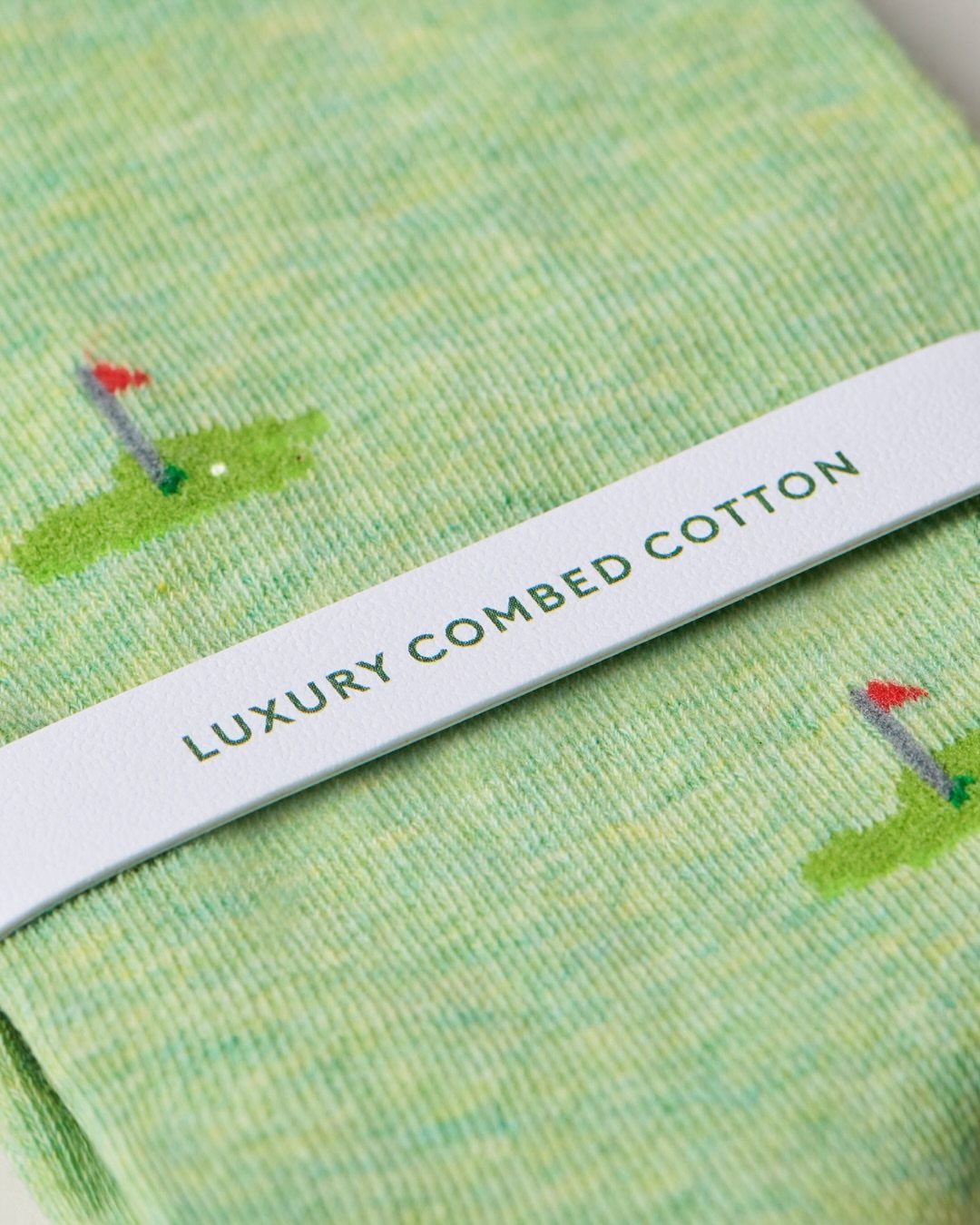 Green golf-themed socks with a luxury combed cotton paper band wrap.