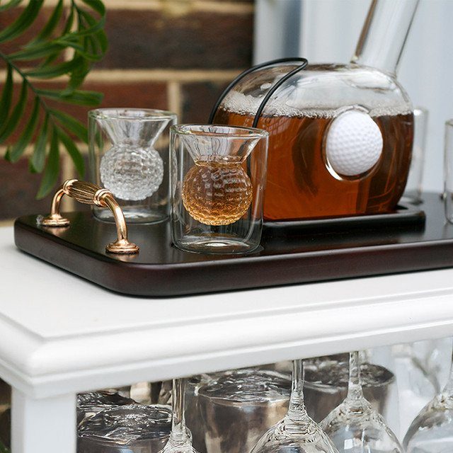 Golf ball shaped glassware and decanter set on a dark wooden tray