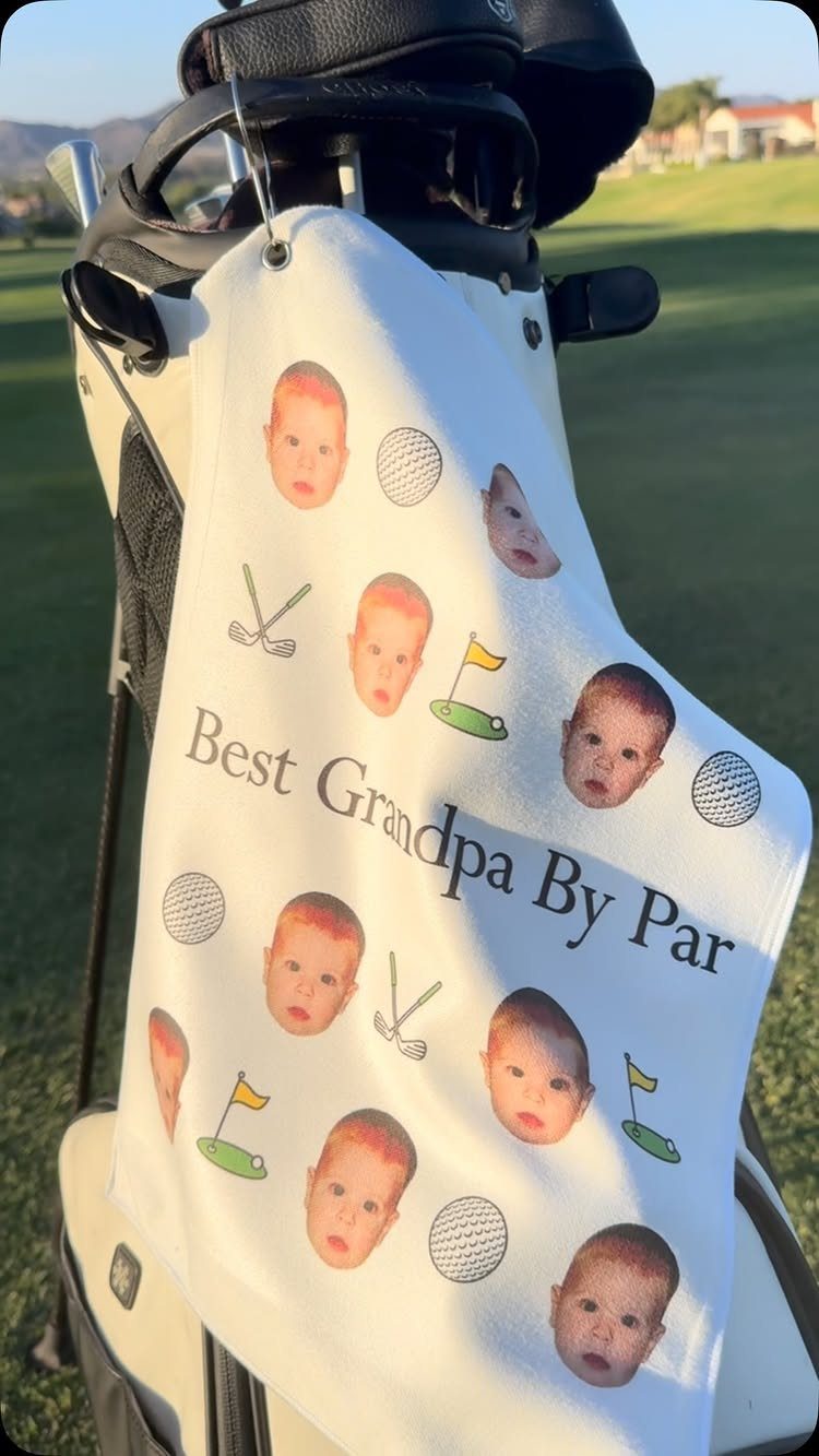 White personalized golf towel with baby faces and text hanging on golf bag