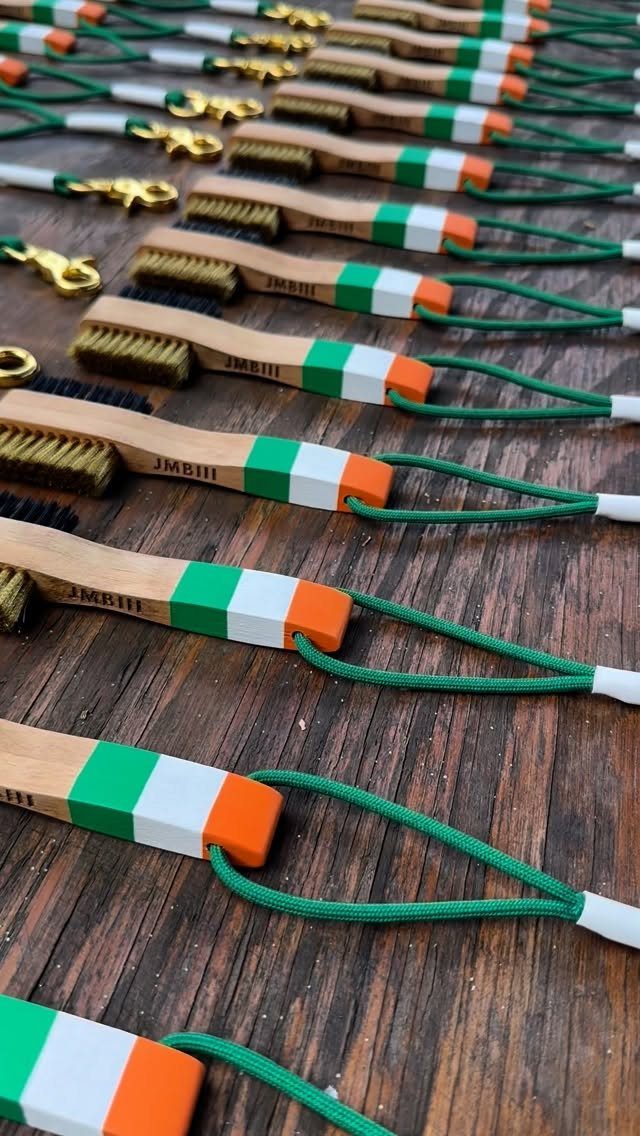 Wooden golf club brushes with tricolor handles and green cords on wood.
