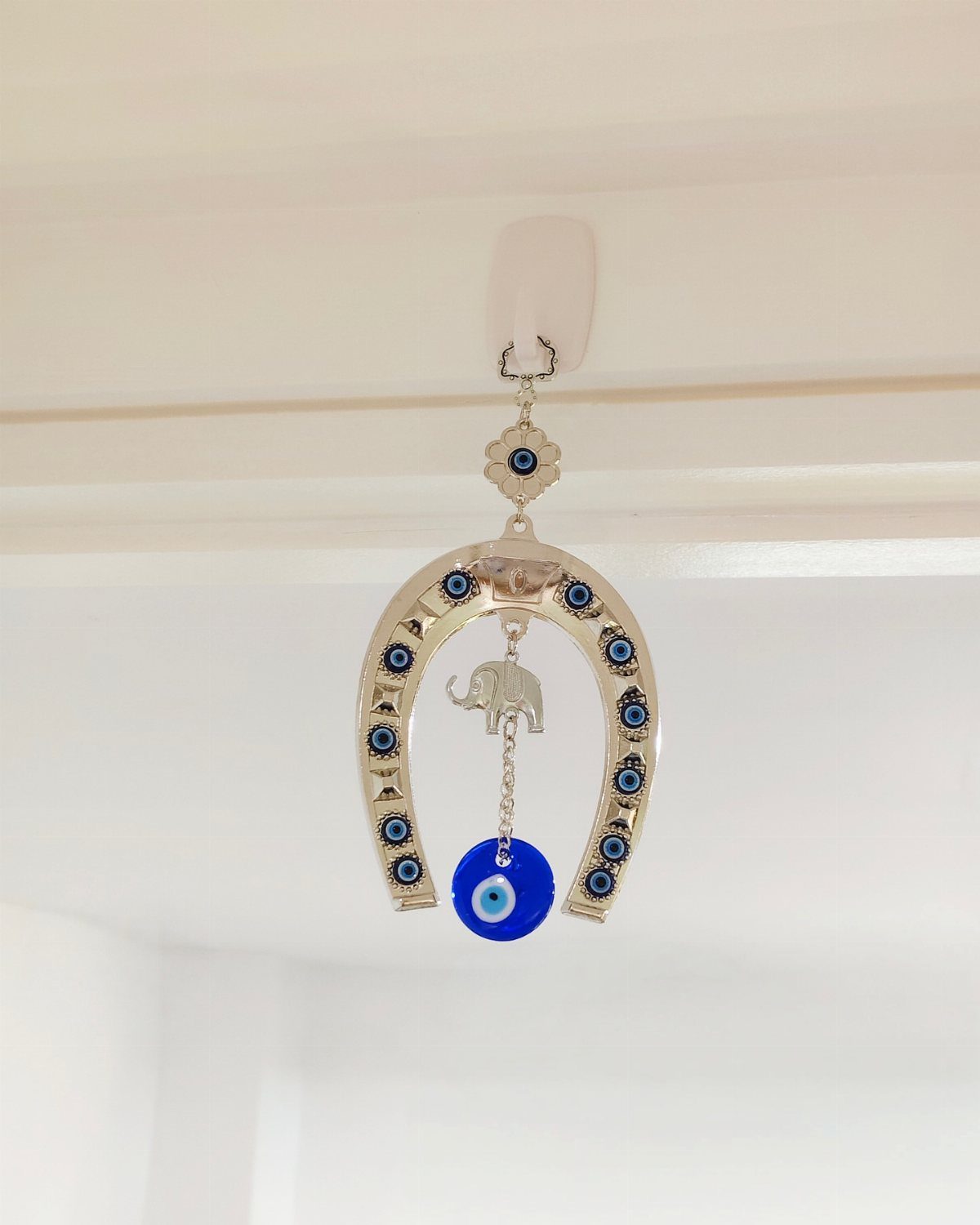 Gold horseshoe ornament with blue evil eye beads and a silver elephant charm.