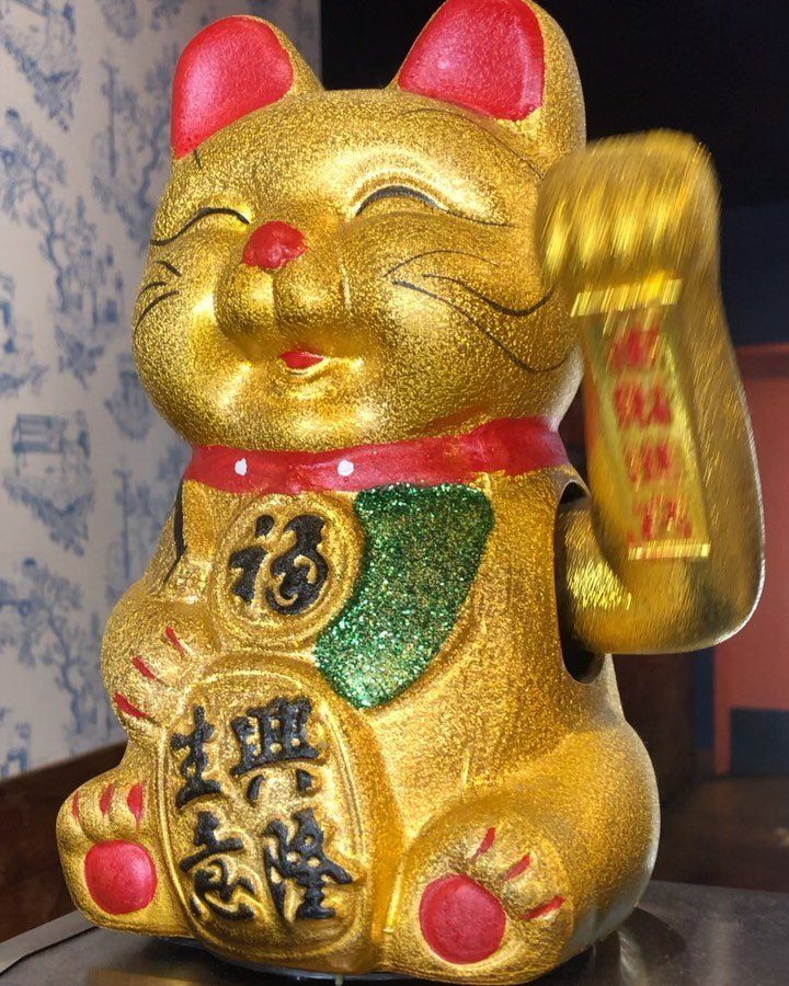 Golden Maneki-neko lucky cat figurine holding a large gold coin with Japanese characters.