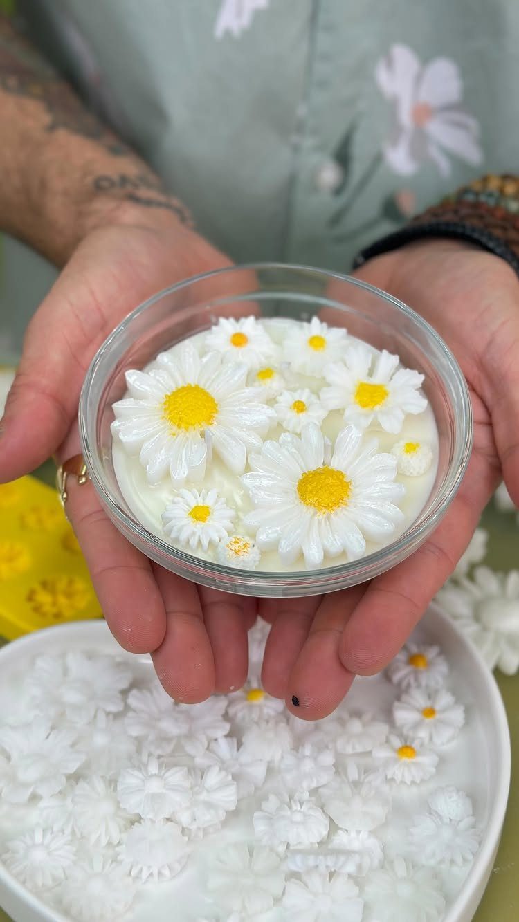 White candle with daisy wax flowers held in a clear glass bowl