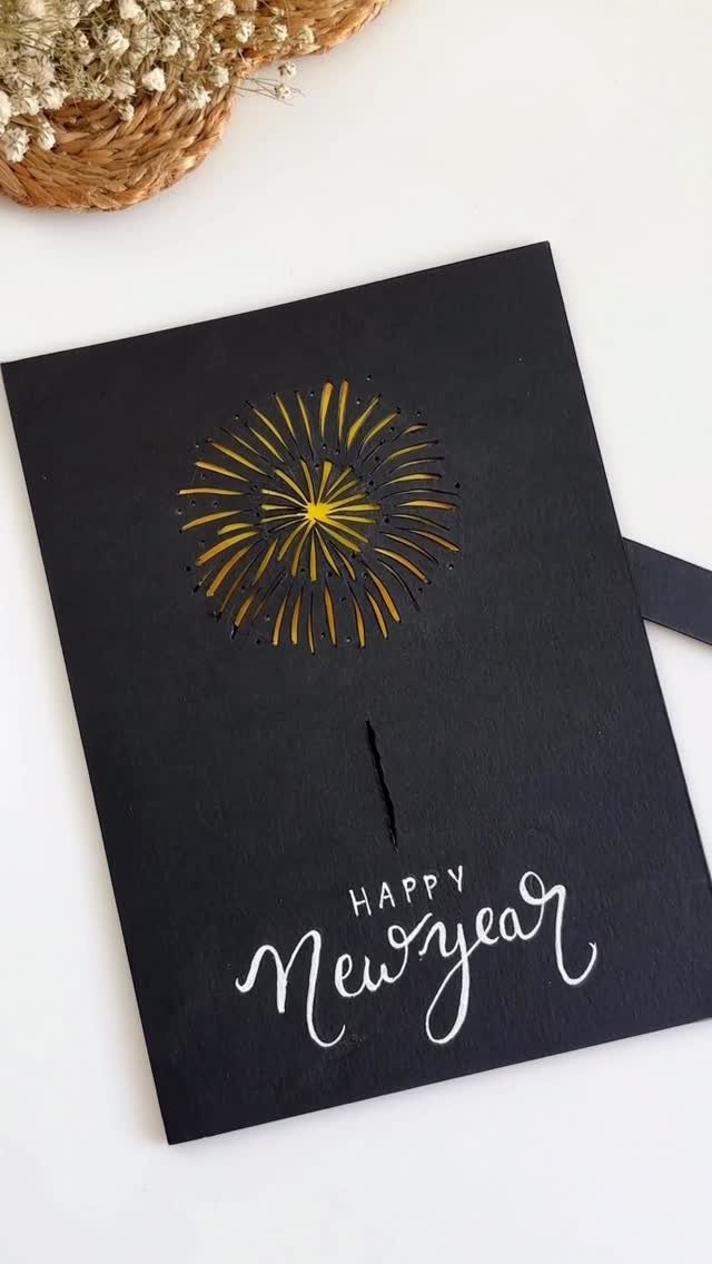 Black New Year greeting card with a yellow firework cutout and white calligraphy.