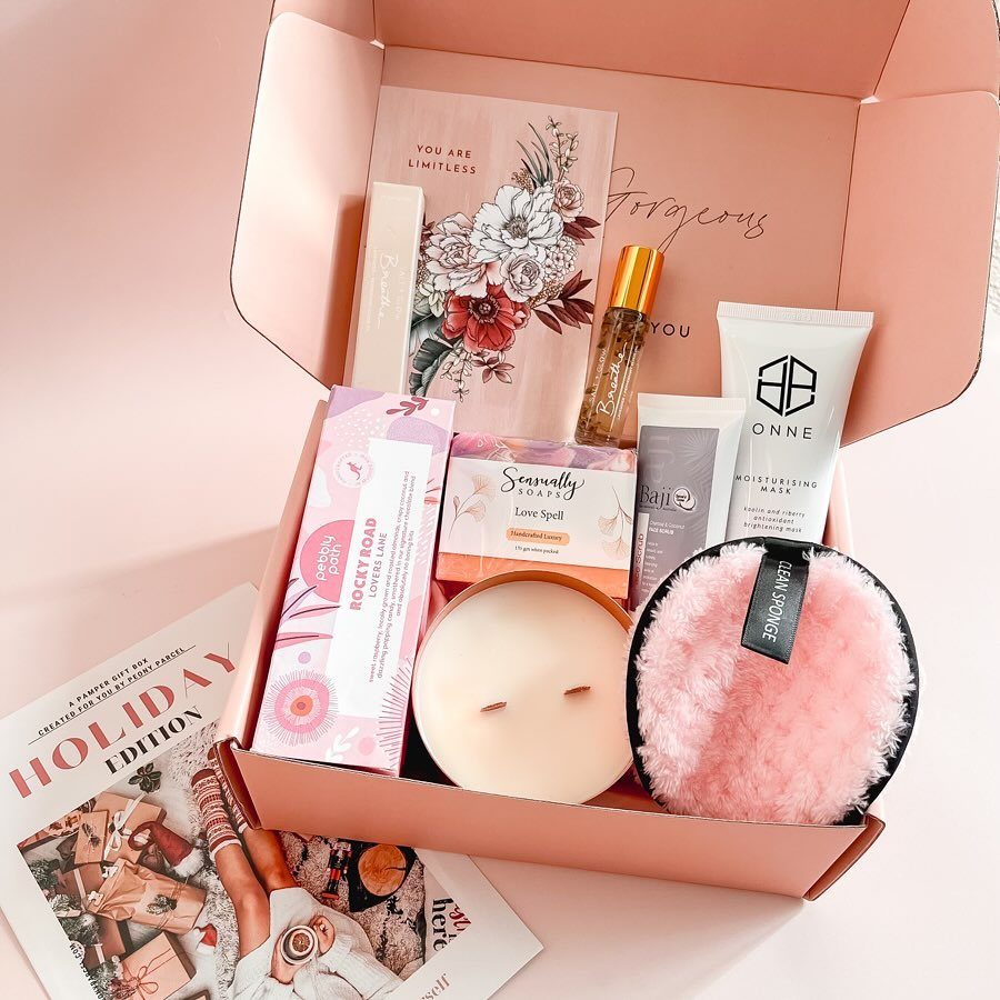 Pink beauty gift box containing skincare, a candle, and a fluffy sponge.