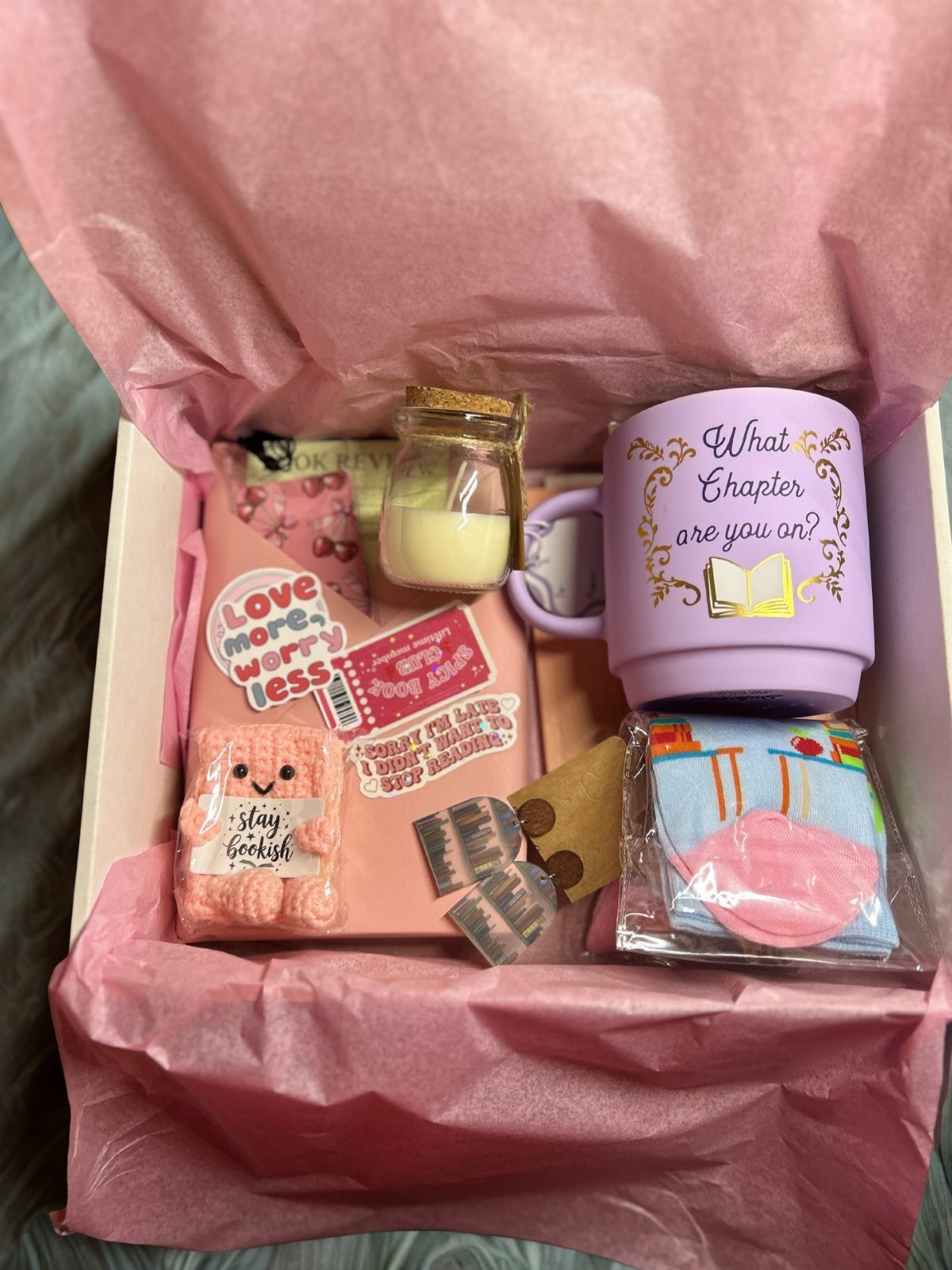 Book-themed gift box with a purple mug, candle, notebook, and plush toy.