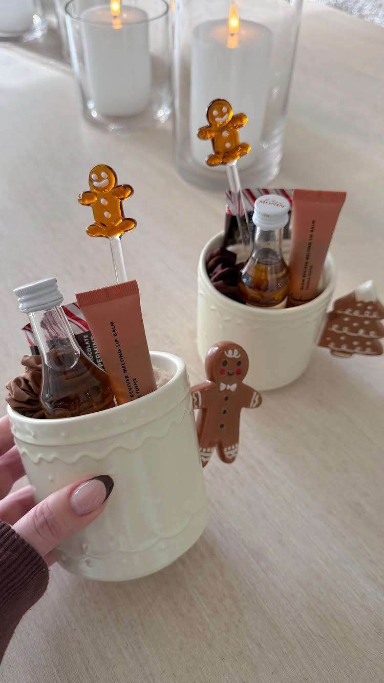 Small white ceramic gift pots filled with miniature bottles and gingerbread stirrers.