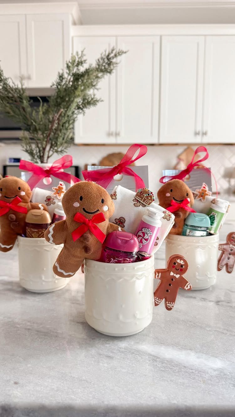 White ceramic mugs filled with gingerbread plushies and small treats as holiday gifts.
