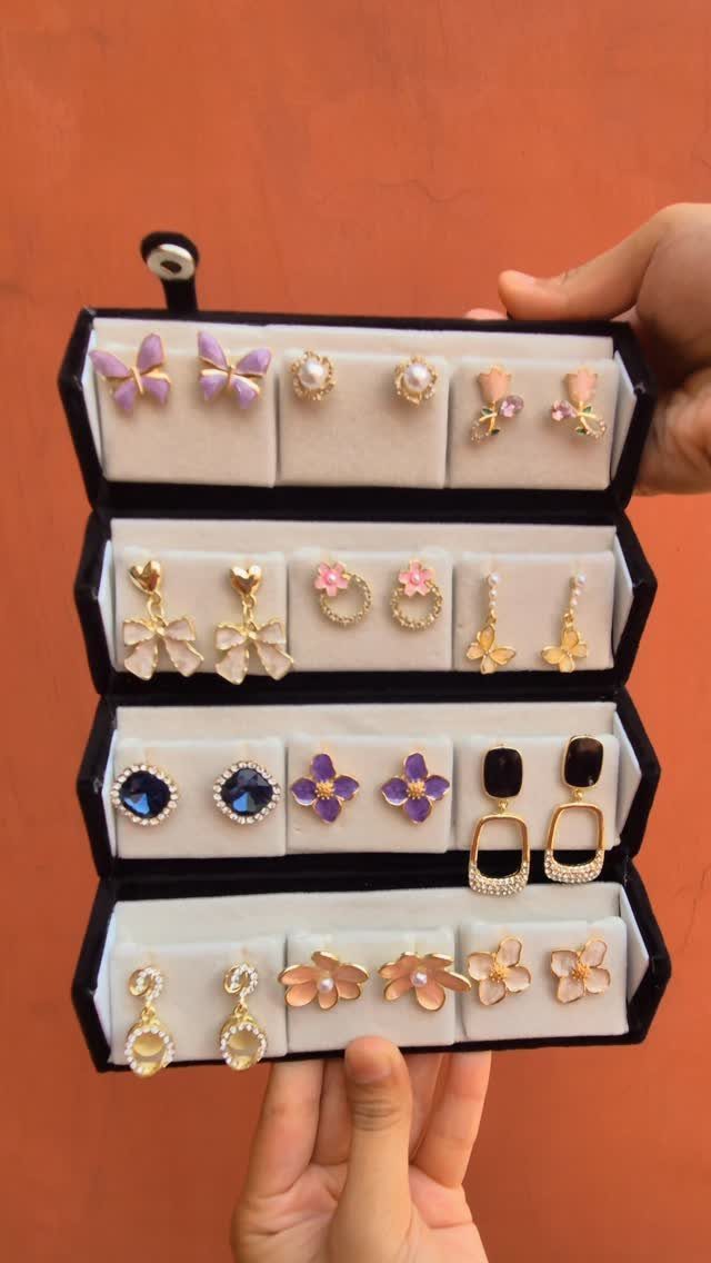 Jewelry organizer held by hands showing a variety of colorful decorative earrings