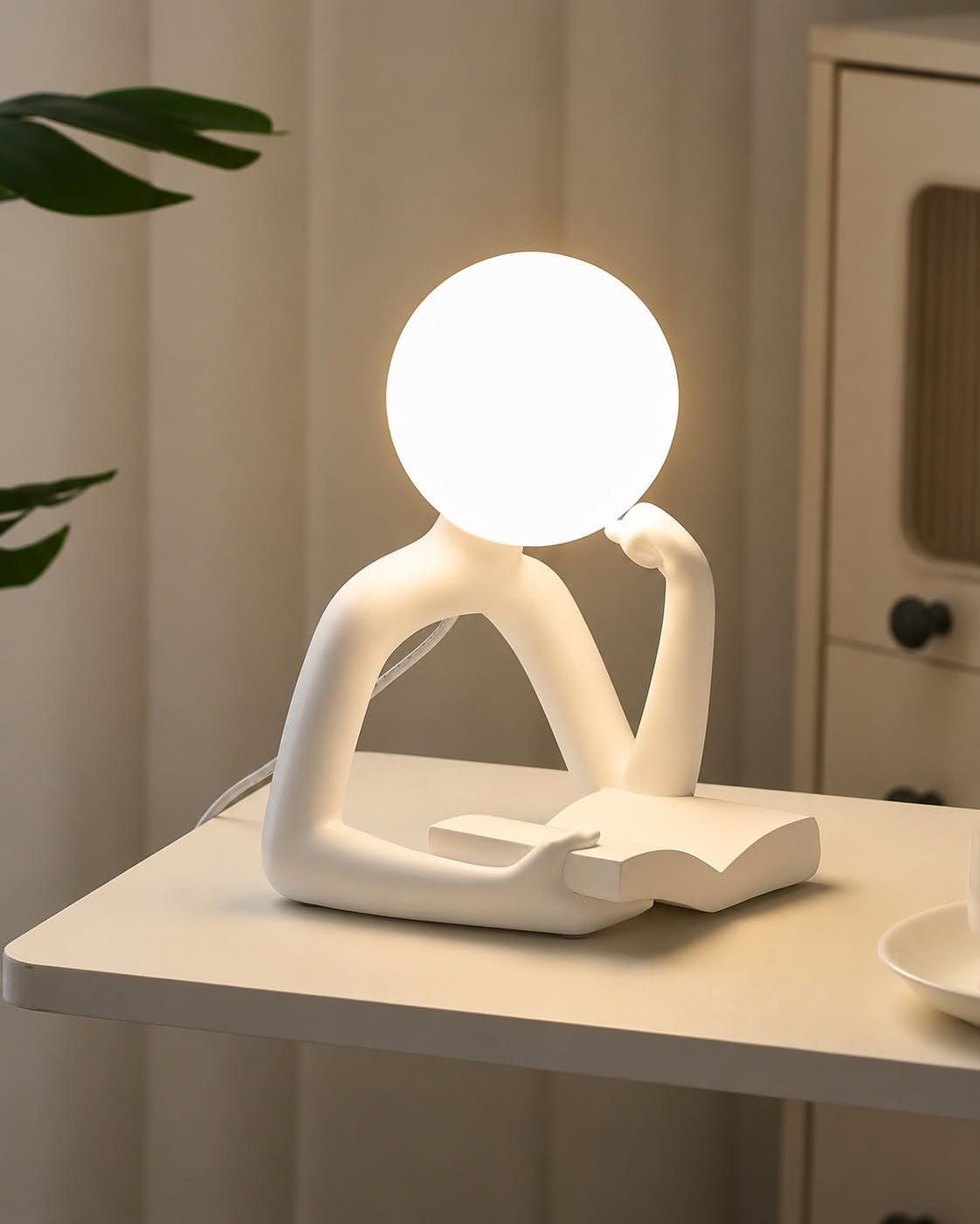 Minimalist white reading lamp shaped like a person with a glowing sphere head.
