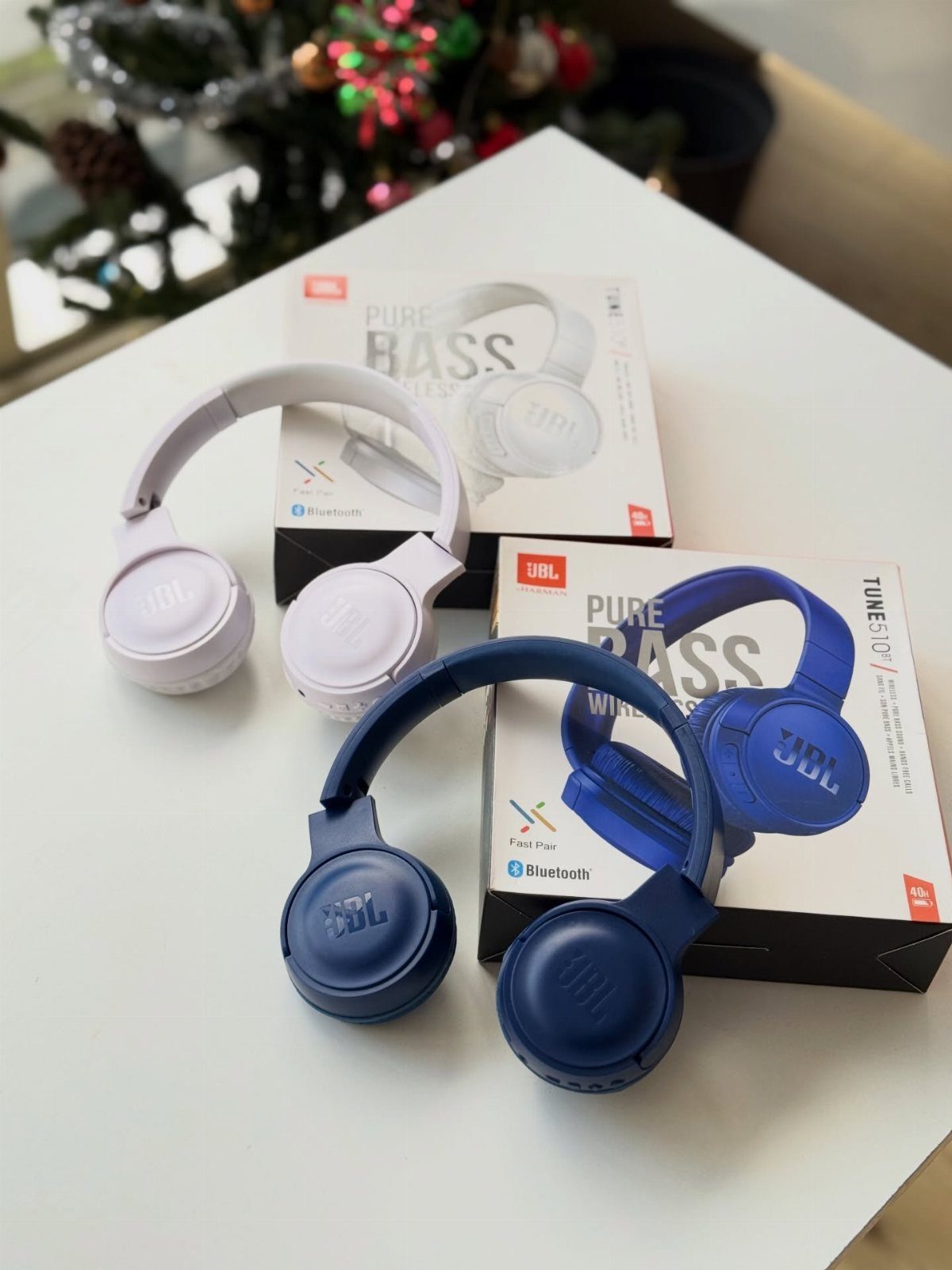 White and blue wireless headphones with their packaging on a white table.