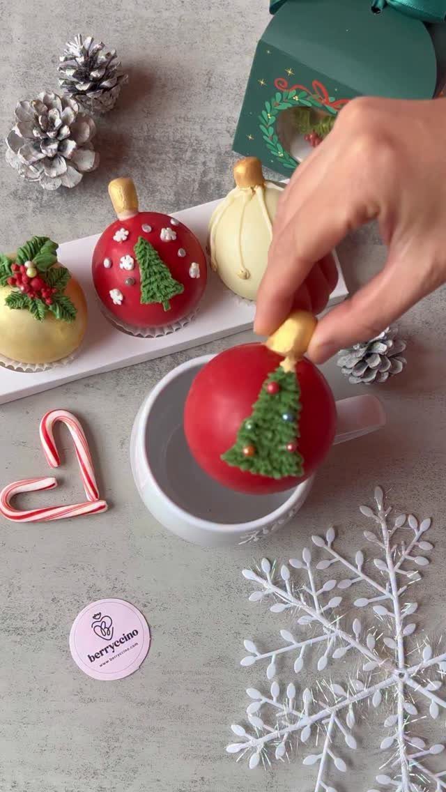 Red chocolate bomb with a green tree being placed into a white mug.