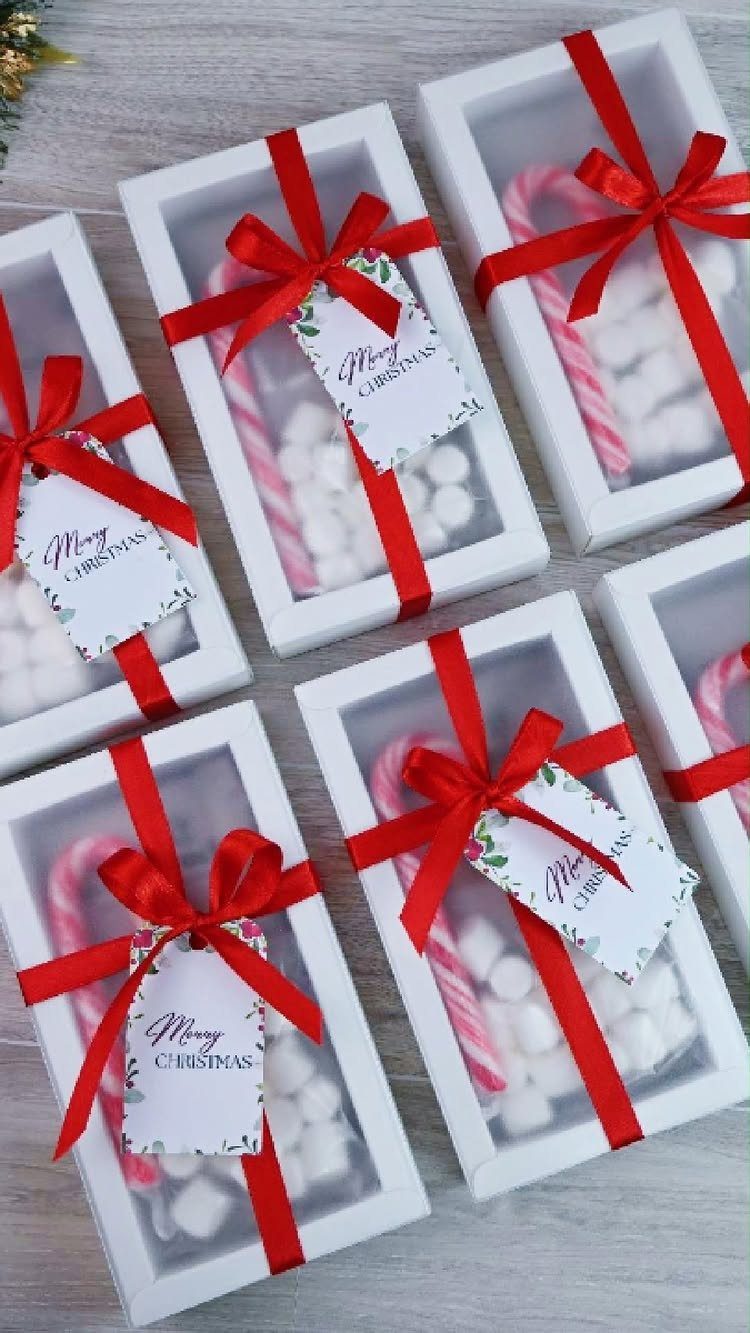 White gift boxes containing marshmallows and candy canes tied with red ribbons.