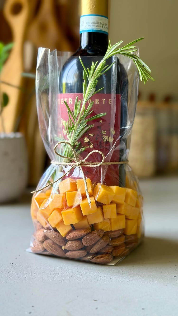 Wine bottle, cheese cubes, and almonds in a clear cellophane gift bag.