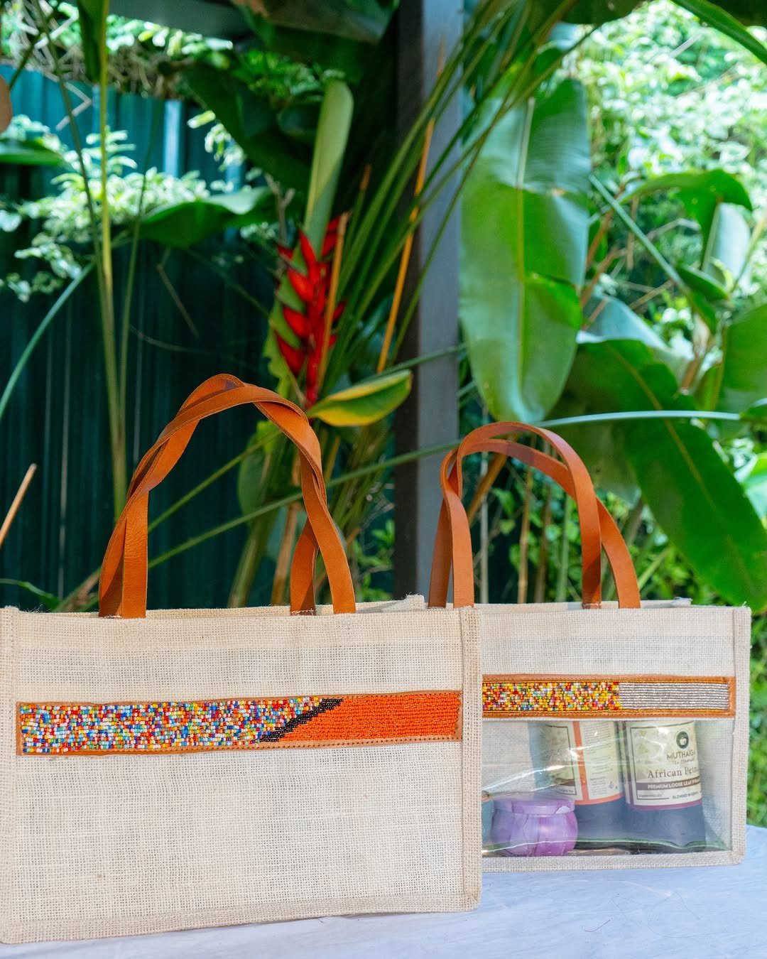 Two jute tote bags, one containing a bottle of wine and a candle.