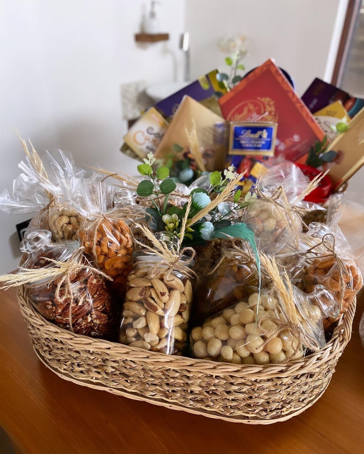 Woven wicker basket filled with clear bags of assorted nuts and dried fruits.