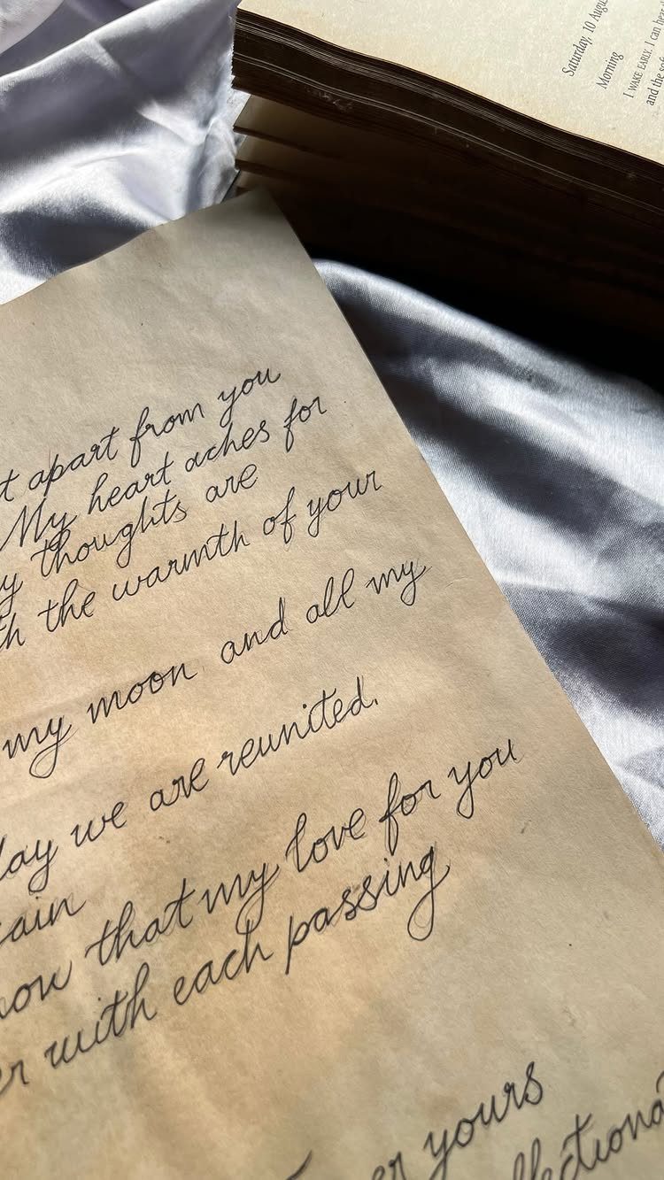 Handwritten cursive letter on aged paper resting on white fabric beside a book