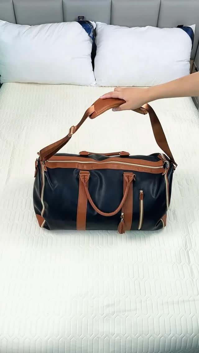 Navy blue duffel bag with brown leather handles on a white bed