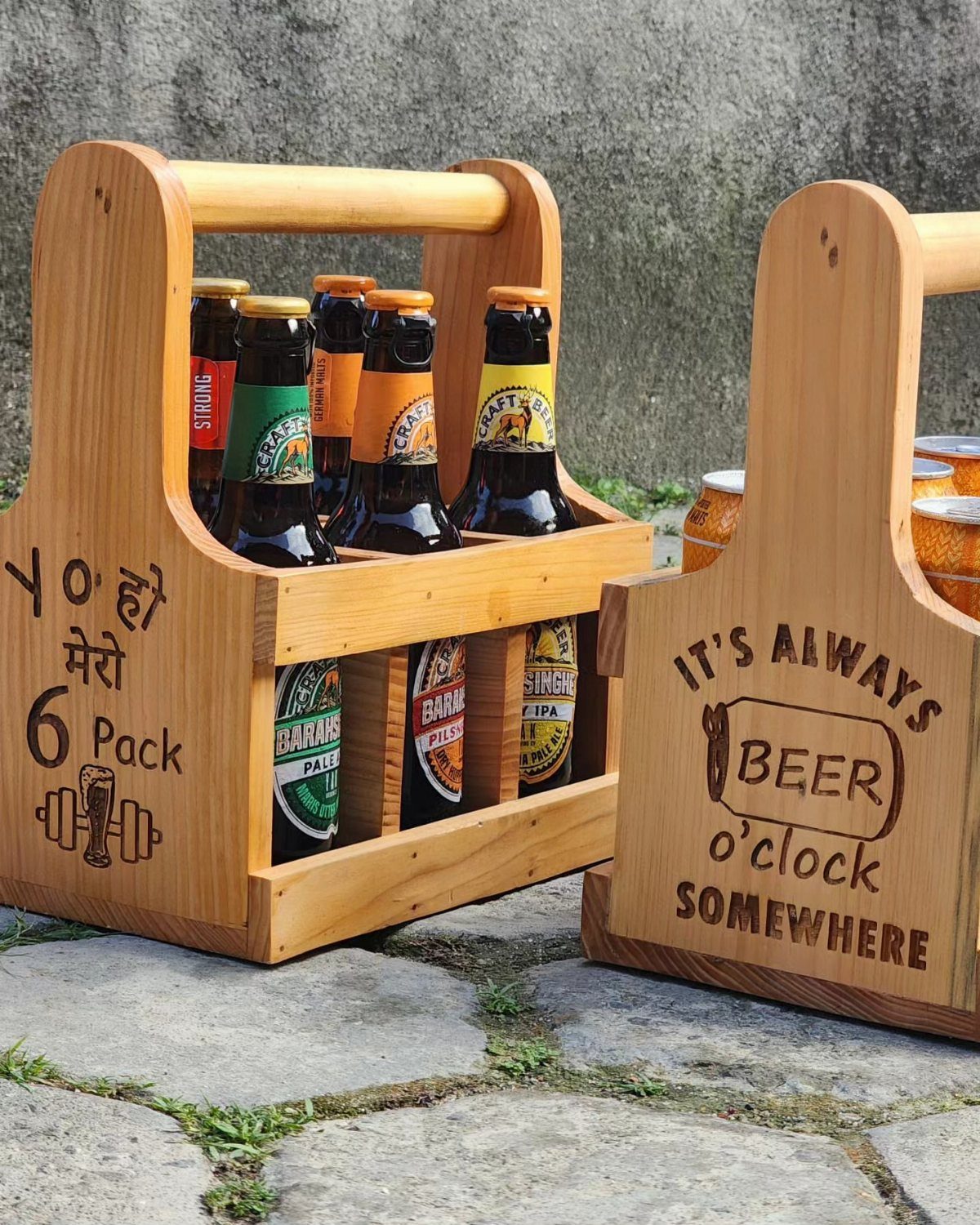 Wooden beer caddies holding glass bottles on a stone pavement outdoors.