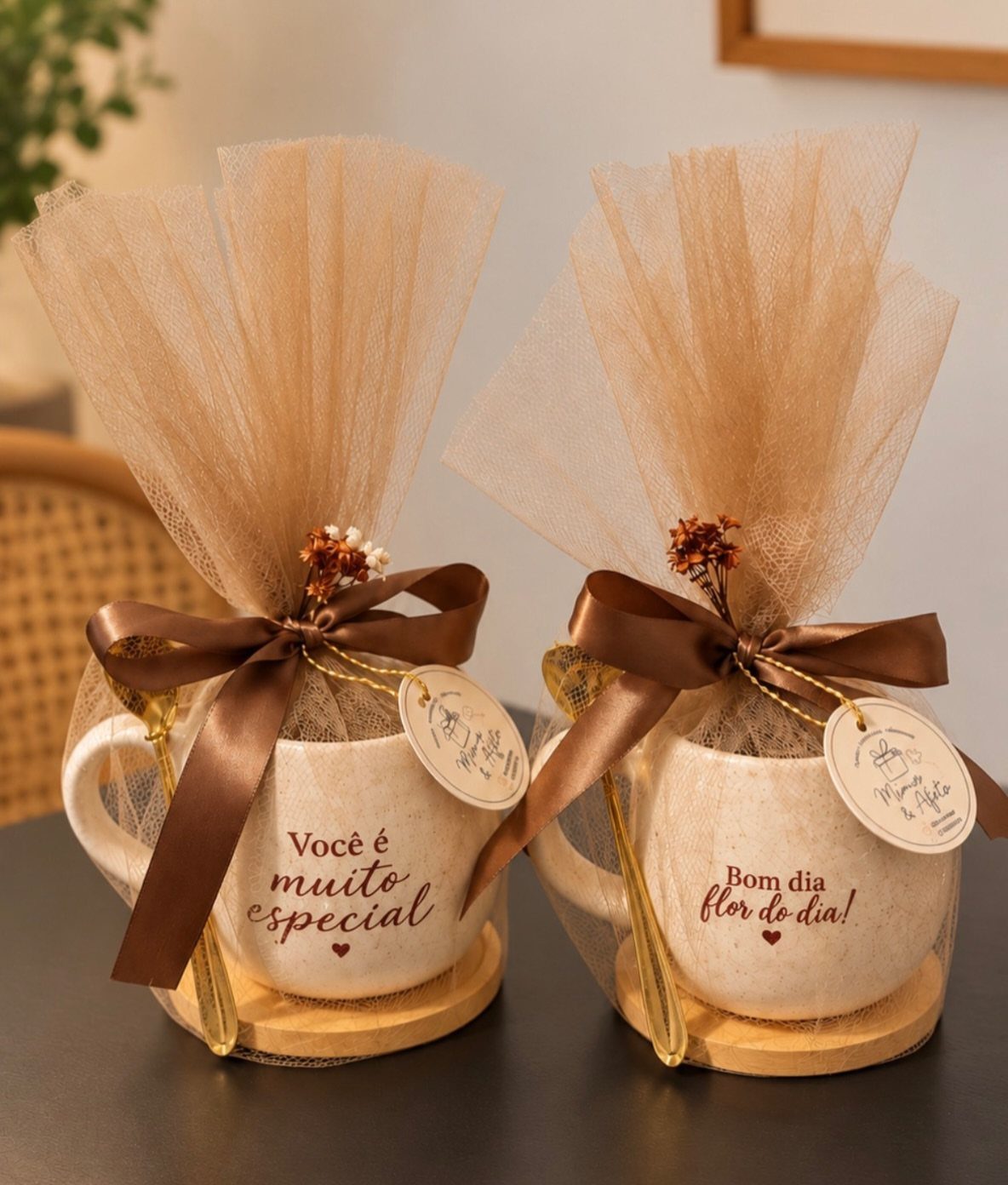 Two white personalized mugs wrapped in beige tulle with brown ribbons and tags.