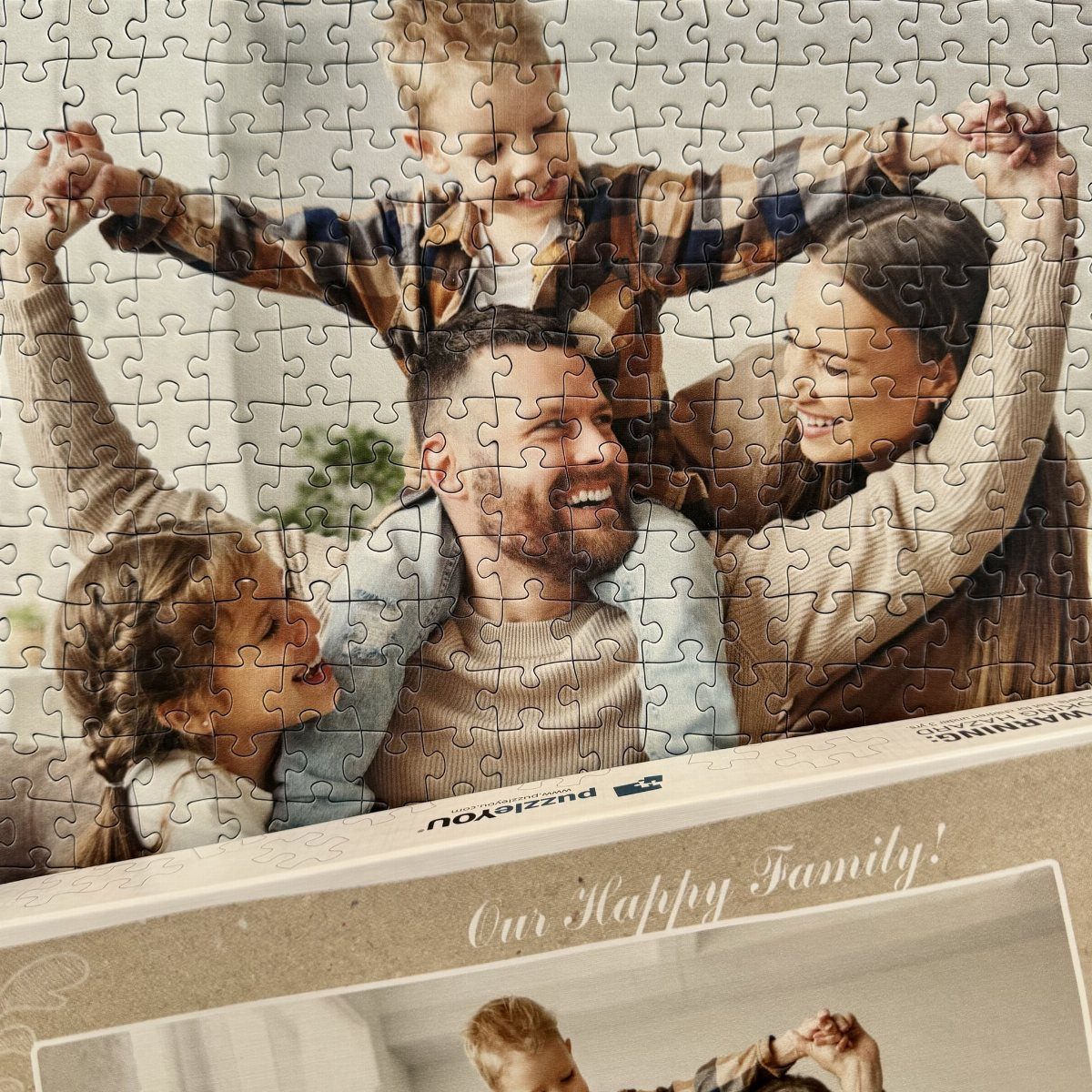 Completed jigsaw puzzle showing a happy family resting on its original packaging box.