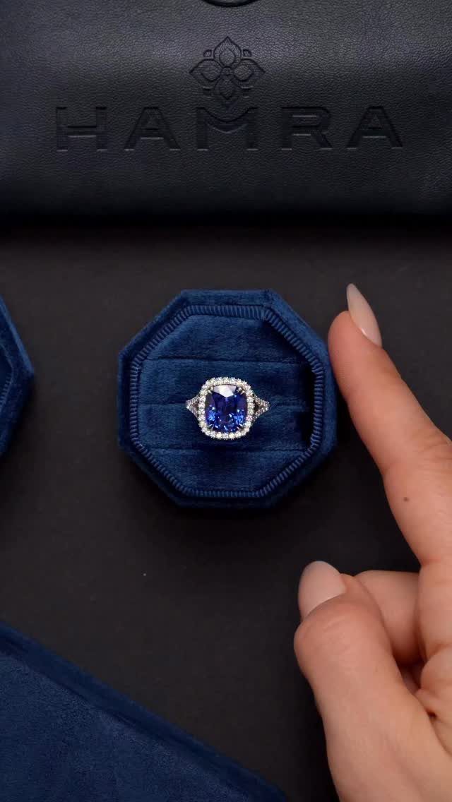 Blue sapphire diamond ring in a velvet box with a hand pointing